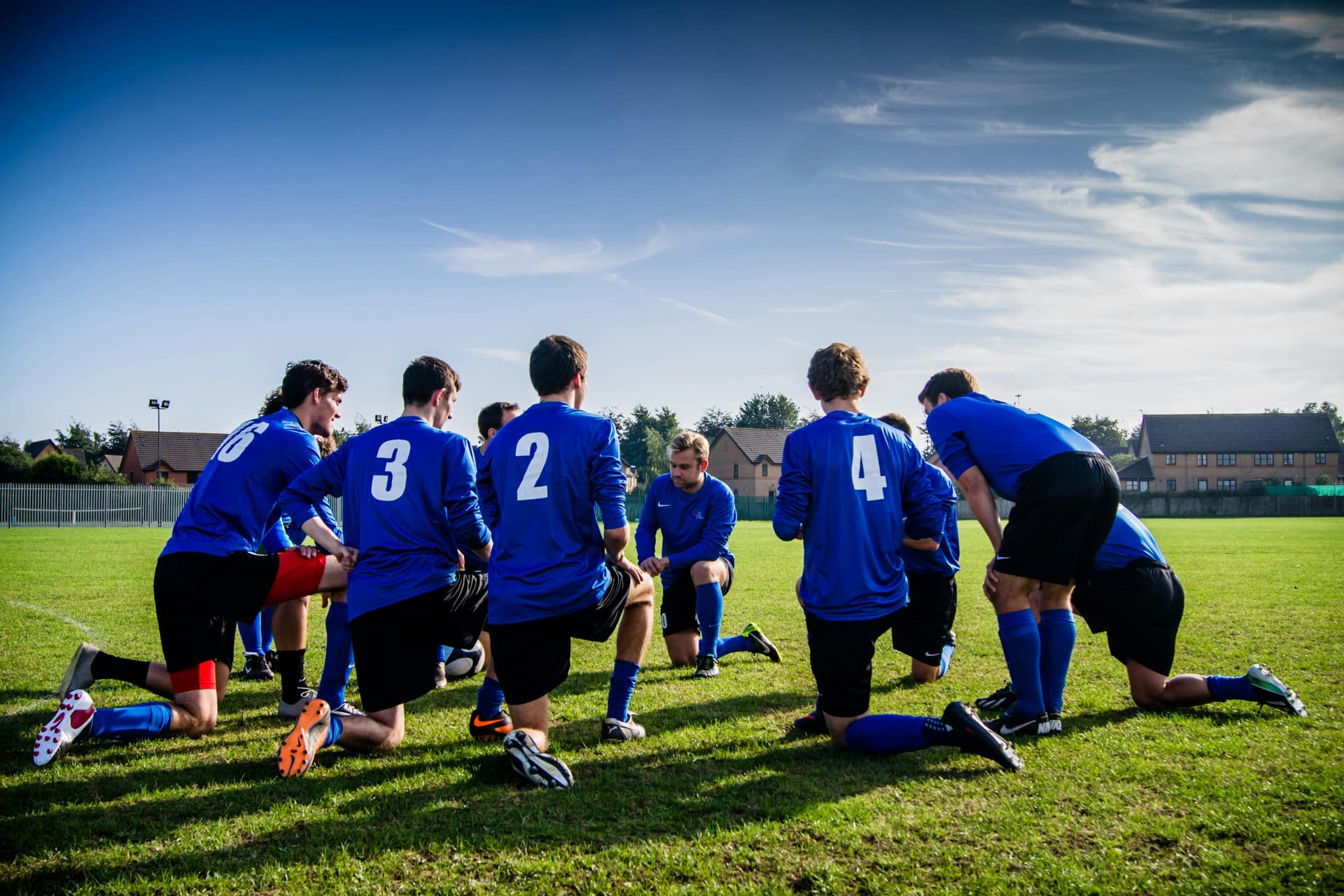 Soccer team in blue jerseys huddled together on field