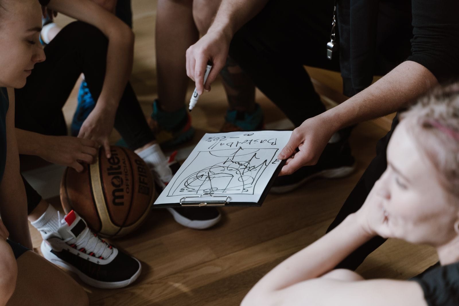 Coach holding a clipboard with a play diagram during a team huddle