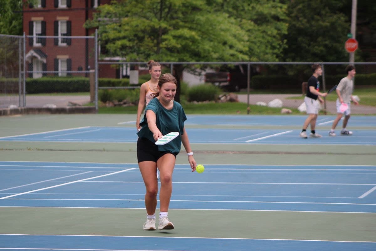 Two players mid-rally on outdoor pickleball courts