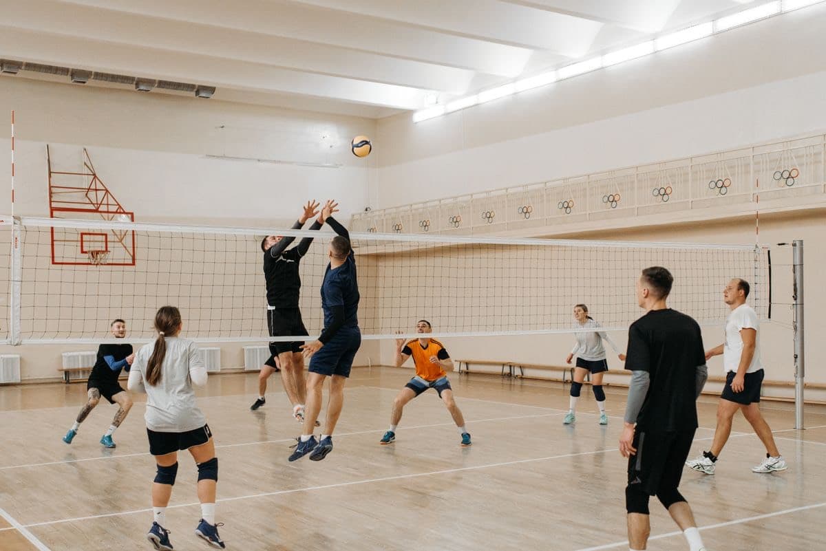 Co-ed volleyball match in a bright gym